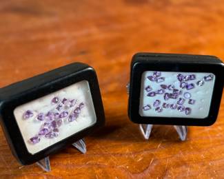 This lot features two (2) containers full of amethyst gemstones in various sizes and cuts. 

