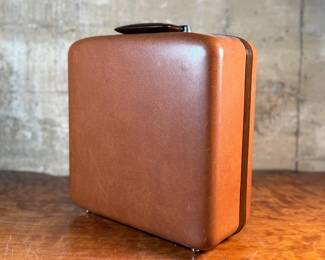 This lot features a vintage Smith Corona Silent-Super portable typewriter, circa 1950s. It has a khaki-toned body and forest green keys, and is shown with its original carrying case. 

