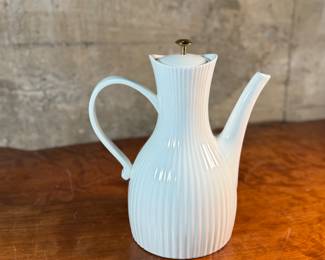 This lot features a vintage Ernest Sohn Creations "Doric" line white ribbed ceramic coffee server or teapot. It was designed by Ernest Sohn and produced by Hall China in the 1950s. This model typically holds around 10 to 12 cups of coffee or tea and measures, 12” H x 10” W x 6” D.

