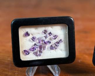 This lot features two (2) containers full of amethyst gemstones in various sizes and cuts. 

