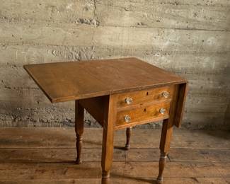 This lot features an antique drop-leaf side table with two dove-tailed drawers. This table measures (closed), 28.5” H x 19.5” W x 20.75” and each leaf adds an additional 11” of width. 

