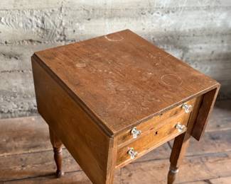 This lot features an antique drop-leaf side table with two dove-tailed drawers. This table measures (closed), 28.5” H x 19.5” W x 20.75” and each leaf adds an additional 11” of width. 

