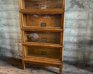 This lot features a stacking barrister bookcase manufactured by Globe Wernicke, dating back to the early 1900s. This bookcase in particular has a total of eight (8) pieces – 6 stacking bookcases, a base, and a topper. This piece measures from top to bottom, 90” H x 34” W x 11” D.

