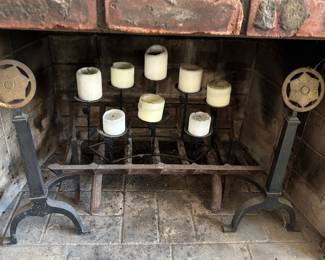 Decorative pair of andirons; between, a well-loved fire-log rack; atop the rack, to add coziness thru the warmer months, a decorative semicircle multi-pillar candle holder
