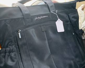 Table filled with Harley Davidson items including this new bag. 