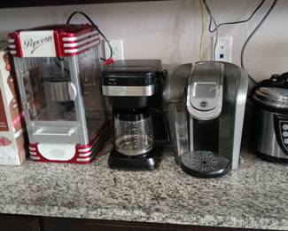 several kitchen appliances, including a Frigidaire theater-style kettle popcorn maker, coffee makers, and a pressure cooker