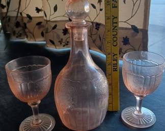 We have over 100 pieces of pink depression glass by Hocking Company, made in the 1930s before merging with Anchor to become Anchor Hocking.  Almost all are the Mayfair Open Rose rose pattern.  Pictured here is a very rare and hard to find decanter with 2 stemmed glasses. 