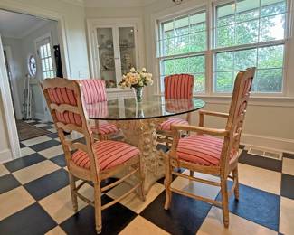 Round glass-top dining table with a sculptural base and a set of four matching vintage wooden armchairs with  upholstered cushions