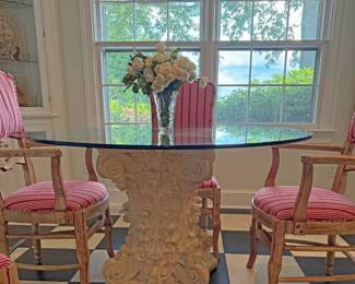 Round glass-top dining table with a sculptural base and a set of four matching vintage wooden armchairs with  upholstered cushions