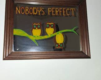 vintage 1970s framed mirror featuring an owl design and the phrase "Nobody's Perfect".
Design: The mirror features three stylized owls on a branch, with one of the owls depicted upside down. The text "NOBODY'S PERFECT" is printed above the owls.
Origin: These mirrors were popular in the 1970s and are often considered kitsch or retro decor. Some variations, like metal wall hangings, were made by companies such as Enesco Imports in 1976.
Collectibility: The item is a collector's piece from the 1970s–80s era and is a sought-after vintage item.