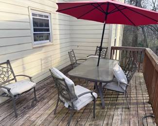 Patio set, including umbrella, glass table, and chairs