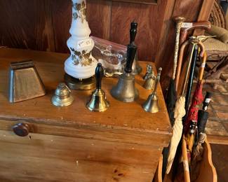 Collection of antique brass bells and vintage umbrellas and walking canes.