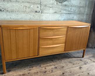 This lot features the Orvar sideboard by Scandinavian Designs. Crafted in teak, this cabinet measures, 29.5” H x 66” W x 20” D. Three large drawers and two cabinets provide ample space for hosting and dining accoutrement.

