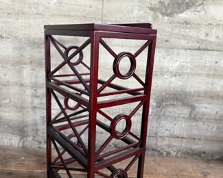 This lot features a library book stand, made of teak with a mahogany finish. This stand measures, 40.5” H x 20” W x 14” D.  The simple neoclassical fretwork on the sides and back gives it great visual distinction. Wide glass shelves provide ample storage, with a special tilting shelf on top for an atlas, dictionary or other frequently consulted volumes. All glass inserts included (not photographed).

