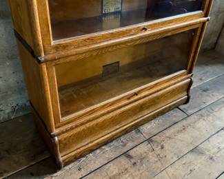 This lot features a stacking barrister bookcase manufactured by Globe Wernicke, dating back to the early 1900s. This bookcase in particular has a total of five (5) pieces – 3 stacking bookcases, a base, and a topper. This piece measures from top to bottom, 49.5” H x 34” W x 11” D.

