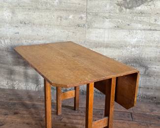This lot features a stunning solid oak drop-leaf table, possibly manufactured by Gustav Stickley (no maker sticker present). This table measures (open), 30” H x 40” W x 42” D and (closed), 30” H x 14” W x 42” D.

