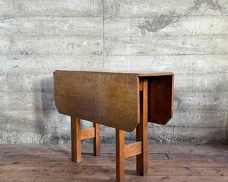 This lot features a stunning solid oak drop-leaf table, possibly manufactured by Gustav Stickley (no maker sticker present). This table measures (open), 30” H x 40” W x 42” D and (closed), 30” H x 14” W x 42” D.

