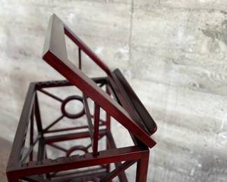 This lot features a library book stand, made of teak with a mahogany finish. This stand measures, 40.5” H x 20” W x 14” D.  The simple neoclassical fretwork on the sides and back gives it great visual distinction. Wide glass shelves provide ample storage, with a special tilting shelf on top for an atlas, dictionary or other frequently consulted volumes. All glass inserts included (not photographed).

