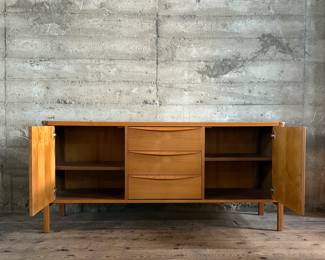 This lot features the Orvar sideboard by Scandinavian Designs. Crafted in teak, this cabinet measures, 29.5” H x 66” W x 20” D. Three large drawers and two cabinets provide ample space for hosting and dining accoutrement.

