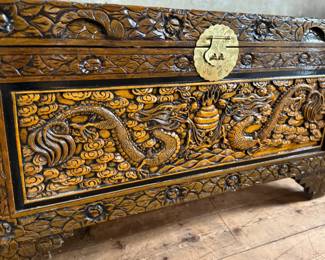 This lot features a Chinese hand-carved camphor wood chest. The chest is made of camphor wood, which is naturally moth-resistant, making it a practical storage solution for clothing or blankets. It features intricate carvings, including dragon panels surrounded by floral or cloud motifs, common in Chinese design. This chest measures, 22.5” H x 39.5” W x 21” D.

