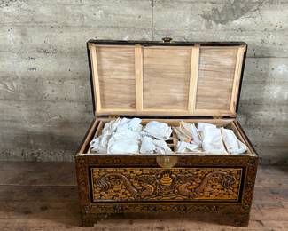 This lot features a Chinese hand-carved camphor wood chest. The chest is made of camphor wood, which is naturally moth-resistant, making it a practical storage solution for clothing or blankets. It features intricate carvings, including dragon panels surrounded by floral or cloud motifs, common in Chinese design. This chest measures, 22.5” H x 39.5” W x 21” D.

