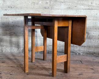 This lot features a stunning solid oak drop-leaf table, possibly manufactured by Gustav Stickley (no maker sticker present). This table measures (open), 30” H x 40” W x 42” D and (closed), 30” H x 14” W x 42” D.

