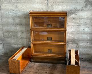This lot features a stacking barrister bookcase manufactured by Globe Wernicke, dating back to the early 1900s. This bookcase in particular has a total of five (5) pieces – 3 stacking bookcases, a base, and a topper. This piece measures from top to bottom, 49.5” H x 34” W x 11” D. This lot also includes two (2) additional stacking bookcases that are missing the glass to be used as is or repaired.

