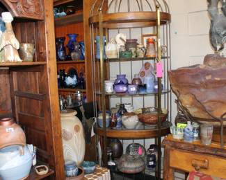 A beautiful brass and wood shelf in the back next to a really cool Fountain sitting on a nice primitive table