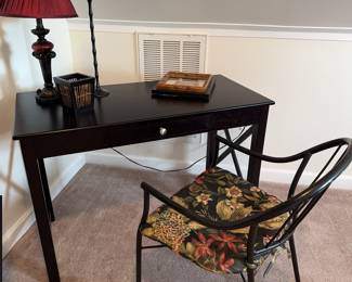 Writing desk setup. Single drawer desk in black, chair with cushion, lamp and small decor.