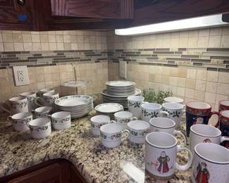 Gold-rimmed Christmas china by Gibson. 8 coffee cups with saucers. 15 assorted Christmas mugs. 8 dinner plates, 8 salad plates. Cookie server.