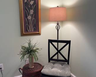 Black accent chair with cushion, floorlamp, framed floral art, wicker basket/stand.