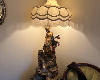 Large gold lady lamp sitting on top of a fountain