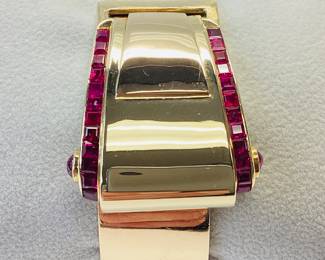 14K BUCKLE BANGLE WITH OVER 3 CTW OF RUBIES 42.2G THIS DESIGNER BUCKLE BANGLE FEATURES 26, 12PT PRINCESS CUT RUBIES AND 2, 15PT CABOCHON RUBIES, ONE ON EACH SIDE. THIS PIECE IS GUARANTEED TO TURN HEADS AT EVERY OCCASION. CARAT WEIGHTS ARE APPROPRIATE.