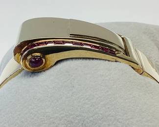 14K BUCKLE BANGLE WITH OVER 3 CTW OF RUBIES 42.2G THIS DESIGNER BUCKLE BANGLE FEATURES 26, 12PT PRINCESS CUT RUBIES AND 2, 15PT CABOCHON RUBIES, ONE ON EACH SIDE. THIS PIECE IS GUARANTEED TO TURN HEADS AT EVERY OCCASION. CARAT WEIGHTS ARE APPROPRIATE.