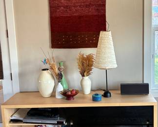 Handwoven wall hanging, light wood media console with sliding glass panel