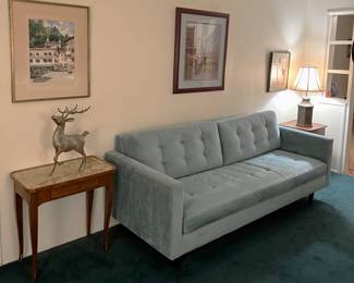 Not only is there a lamp in this photo, but three framed artworks, a statue of a stag, two tables, and the sofa.