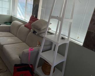 Tall white stand, artificial plant, backpacks, couch