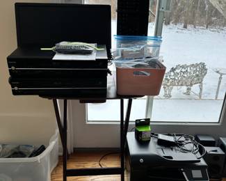 Two VCR/DVD players, a desktop monitor, speakers, a printer and ink, a keyboard, various new, barely used modern day tech devices.