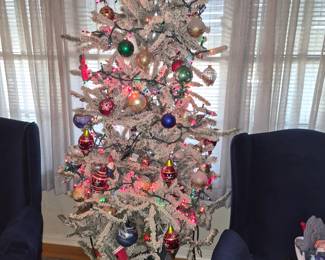 Small, flocked artificial Christmas tree in planter box.