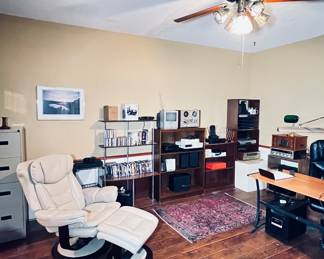 Office area in home with several pieces of furniture, desk,equipment,printers and office supply 