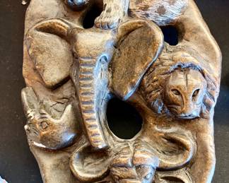 Hand-carved stone relief panel depicting a group of African animals—leopard (or cheetah), lion, elephant, rhinoceros, and buffalo