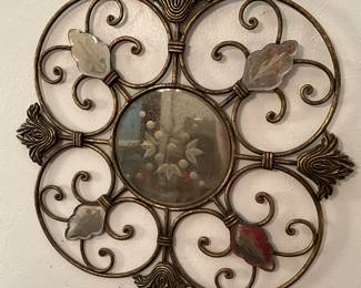 Antique round mirror inside a gold colored frame with rounded corners.