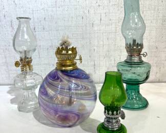vintage miniature clear glass oil lamp, 7"
 a hand-blown art glass oil lamp with an iridescent purple and blue swirl pattern, 5"
a vintage miniature green glass oil lamp, 4"
vintage green glass kerosene lamp, 8"
These items can be shipped.