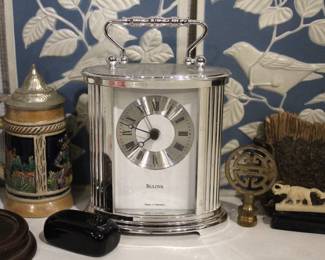 A vintage Bulova quartz carriage clock, in a lot with several other sophisticated trinkets. An embroidered handkerchief 4" x 4", a 2 tier tiny shelf 3.5", and a 1 tier shelf 2", a rock turtle 4", a tiny black pot 1", a small black stone 1" x 2", a mini stein 5", a vintage Bulova quartz carriage clock 6" x 4", an Asian style bottle cap 2.5", a decorative stand 5" x 3", a row of elephants 4" x 1", a mini sewing model 5", a small stone coaster 4.5" x 1", a rock cube 3" x 3", 2 blue and white decorative bird signs 8.5" x 5.5". These items can be shipped