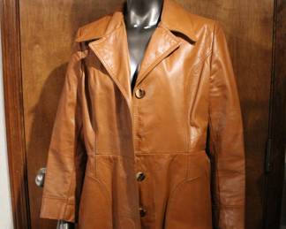 A vintage 1970s brown leather trench coat size S/M with a dagger collar, removable waist tie, and large pockets. This item can be shipped.