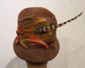 A vintage Charlotte New York brown felt cloche hat with a ribbon and feather accent, 10" brim to brim, 7" tall. This item can be shipped.