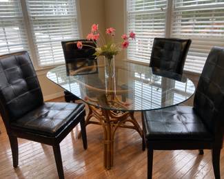 Rattan base glass-top dining table and four faux leather chairs (table and chairs sold separately)