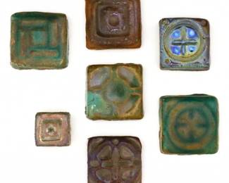 Seven early 20th century Pewabic Pottery tiles.  Square tiles with relief geometric designs and multi-color glazes.  Minor wear, some crazing, one tile with chips to back edges.  Up to 1 3/4" high.
