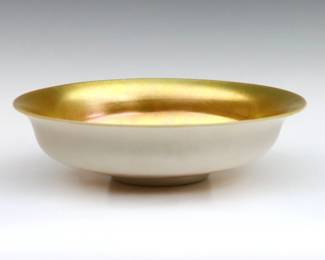 An early 20th century Steuben Art Glass center bowl.  Low footed form with flared rim, Gold Aurene interior and Calcite exterior.  Unsigned.  Minor surface wear, two small darkened spots in interior from production.  10" diameter x 2 1/2" high overall.  NOTE: From the estate of Bill & Barbara Shulhof of Saginaw, Michigan.
