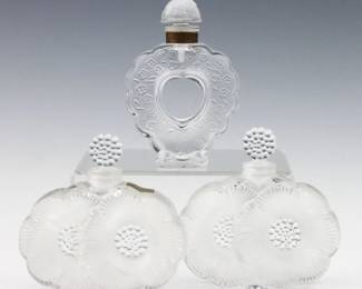 Three mid 20th century Lalique Art Glass perfume bottles.  Includes two "Deux Fleurs" pattern bottles and a "Coeur Joie" pattern bottle for Nina Ricci with frosted accents.  Deux Fleur bottles signed "Lalique France", one with original Gold foil Lalique label, Coeur Joi bottled marked "Nina Ricci / Bottle Made by Lalique".  Minor surface wear.  Up to 4" high.  NOTE: From the estate of Bill & Barbara Shulhof of Saginaw, Michigan.